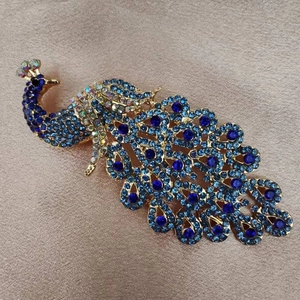 Macro detail of elegant peacock brooch featuring blue crystals and gold plating finish