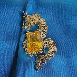 Detailed close-up of a golden dragon brooch featuring a large yellow zircon stone center