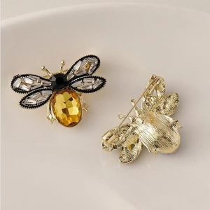 Détail d'une broche abeille montrant le métal doré, la gemme jaune et l'épingle arrière
