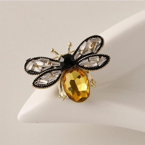Détail de la broche abeille avec cristal jaune et ailes pavées sur un support blanc élégant