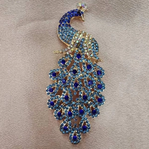 Detail of elegant peacock brooch featuring vibrant blue crystals and golden alloy finish