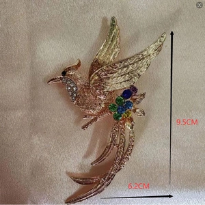 Elegante spilla a fenice con cristalli colorati e placcatura in oro su sfondo di seta