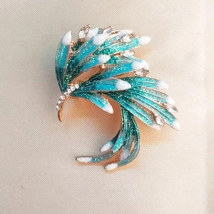 Elegant gold phoenix feather brooch with peacock blue enamel and sparkling rhinestones