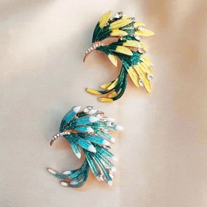 Detail view of enamel feather brooches with gradient colors and rhinestones on silk