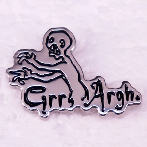 Macro shot of silver enamel zombie pin with artistic Grrr Argh text on white fabric