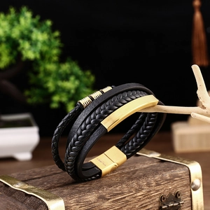 Detail view of multilayer braided leather bracelet with golden beads on a wooden display