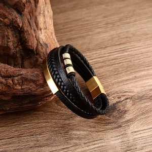 Macro detail of men's multilayer leather bracelet with gold magnetic clasp and metal accents