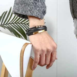 Detail of multi-layer black leather bracelet with gold metal plate on male wrist