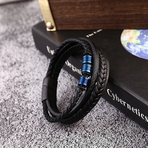 Detail of multi-layer black braided leather bracelet with blue metal tubes on a book