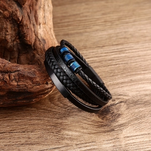 Close-up of black braided leather bracelet with blue metal beads on a wood background