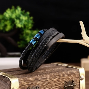 Macro shot of men's multi-layer woven leather bracelet with blue metal accents on wood