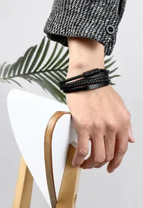Macro detail of men's multilayer braided black leather bracelet with matte metal magnetic clasp