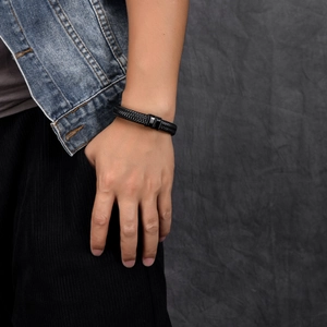 Detail of men's braided black leather bracelet with a textured magnetic steel clasp