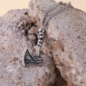 Nordic Viking axe pendant necklace with raven totem on rustic stone background
