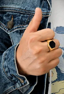 Gros plan d'une bague chevalière hexagonale dorée avec insert noir au style décontracté