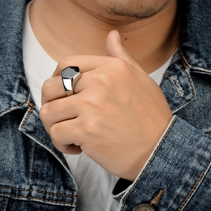 Gros plan d'une bague hexagonale noire pour homme avec finition argentée polie