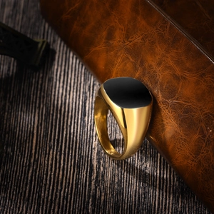 Macro shot of polished gold signet ring with black resin inlay on brown leather