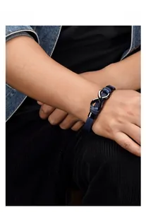 Dettaglio del bracciale in pelle blu intrecciata con simbolo dell'infinito in acciaio