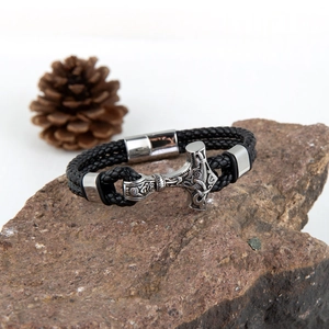 Macro detail of Viking Mjölnir bracelet on stone with braided leather strap and magnetic clasp