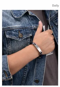 Close-up of men's leather bracelet with a brushed metal plate on a model wearing denim
