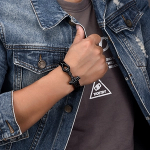 Close-up of black braided leather bracelet featuring a detailed Viking Mjölnir charm