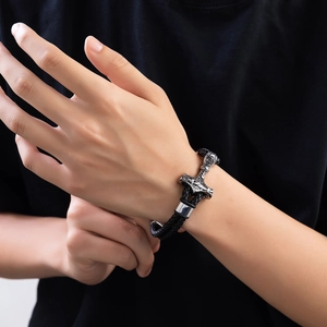 Close-up of woven black leather bracelet with Viking style engraved silver metal clasp