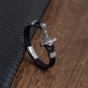 Men's Viking Mjolnir braided leather bracelet with silver Thor's hammer charm on wood