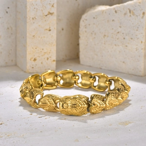 Detailed close-up of gold punk chain bracelet with relief animal head links on stone