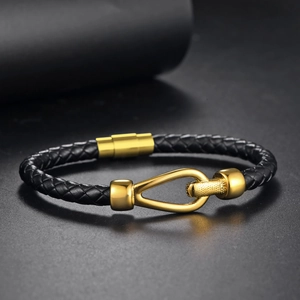 Macro detail of men's braided black leather bracelet with gold horseshoe magnetic clasp