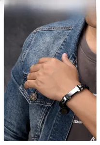 Close-up of a men's braided black leather bracelet featuring a brushed silver metal plate