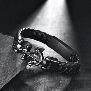 Detail eines schwarzen geflochtenen Lederarmbands für Herren mit Anker auf Stein