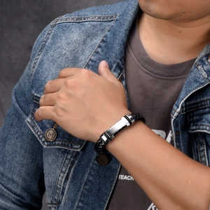 Men's black braided leather bracelet featuring a brushed stainless steel plate on wrist