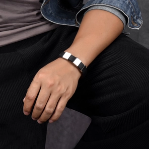 Männliches Model trägt minimalistisches schwarzes Lederarmband mit silberner Metallplatte