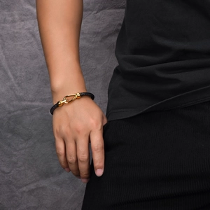 Close-up of braided black leather bracelet with golden horseshoe magnetic steel clasp