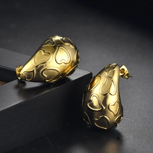 Détail macro de boucles d'oreilles gouttes avec motif cœur gaufré en finition dorée polie