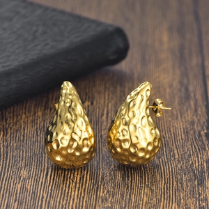 Détails de la texture martelée des boucles d'oreilles goutte dorées et fermoirs papillon