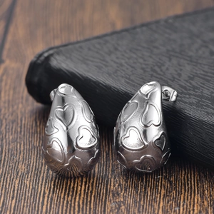 Gros plan détaillé de boucles d'oreilles goutte argentées avec motifs de cœurs gravés