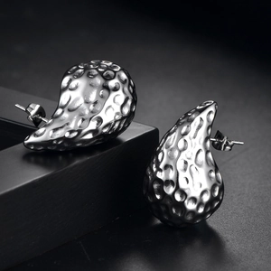 Vue macro de boucles d'oreilles argentées martelées en forme de goutte au design fluide