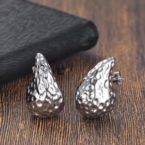 Gros plan de boucles d'oreilles argentées en goutte avec texture martelée sur bois