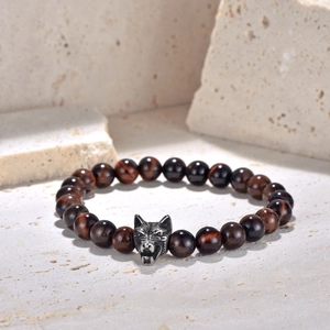 Detailed close-up of red tiger eye beaded bracelet with vintage wolf head charm