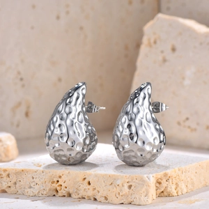 Gros plan sur des boucles d'oreilles gouttes argentées martelées sur pierre naturelle