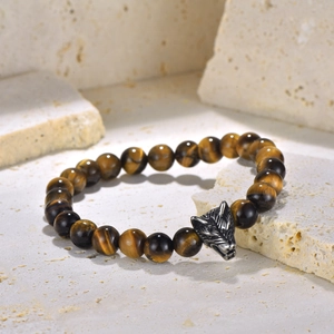 Macro shot of tiger eye beads and a detailed silver wolf head charm on a men's bracelet