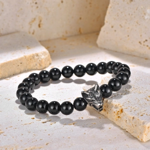 Detailed view of black onyx beads and an antique silver wolf head charm on a men's bracelet