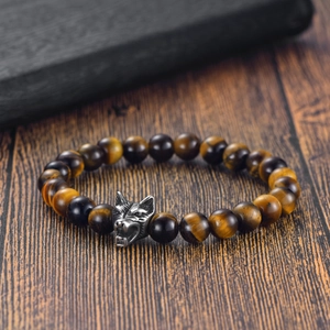 Tiger eye bead bracelet with stainless steel wolf head charm on dark wooden background