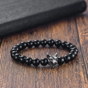 Detail of beaded bracelet with black onyx beads and finely engraved steel wolf head charm