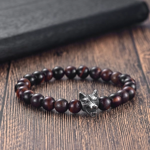 Macro shot of silver wolf head charm on red tiger eye stone beaded bracelet for men