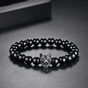 Detailed close-up of a silver wolf head charm on a black onyx beaded bracelet for men
