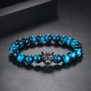 Detailed macro shot of blue tiger eye beads and a stainless steel wolf head charm