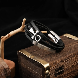 Détail d'un bracelet en cuir multicouche avec croix d'Ankh argentée et plaque sur bois