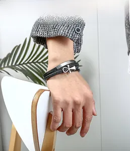 Gros plan d'un bracelet multicouche en cuir pour homme avec croix ankh et plaque métal